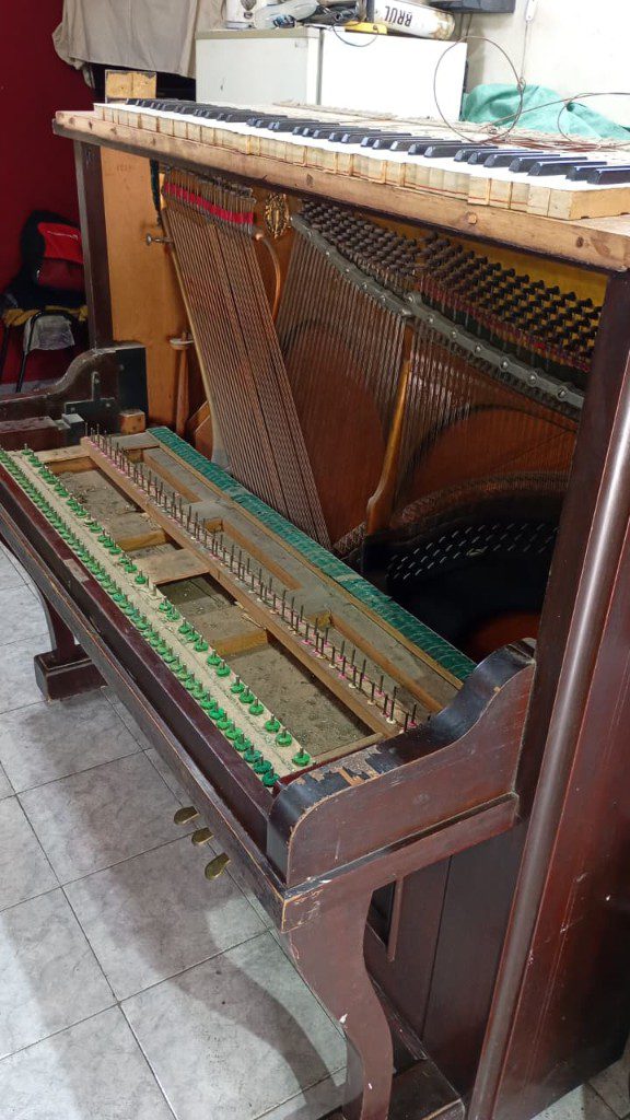 Afinación de piano: cuerdas y clavijas Clavijas y cuerdas de un piano vertical durante la afinación, con el teclado levantado