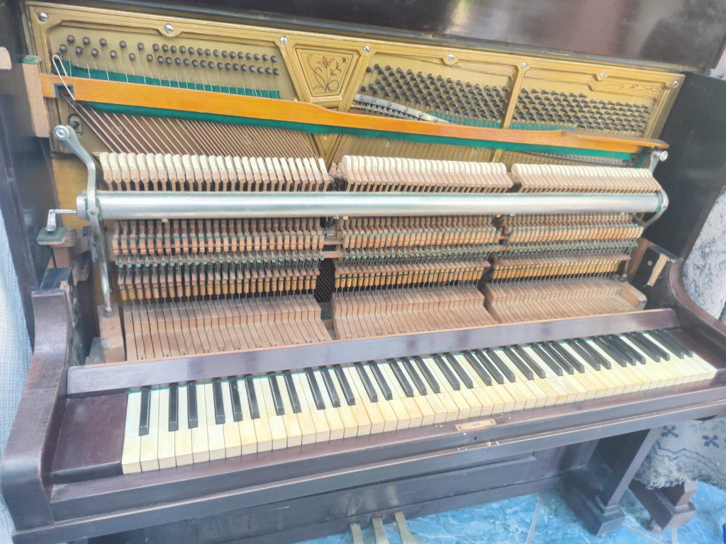 Afinación de piano: mecanismo y teclado Piano vertical abierto para afinación, con el teclado, los martillos y las cuerdas a la vista
